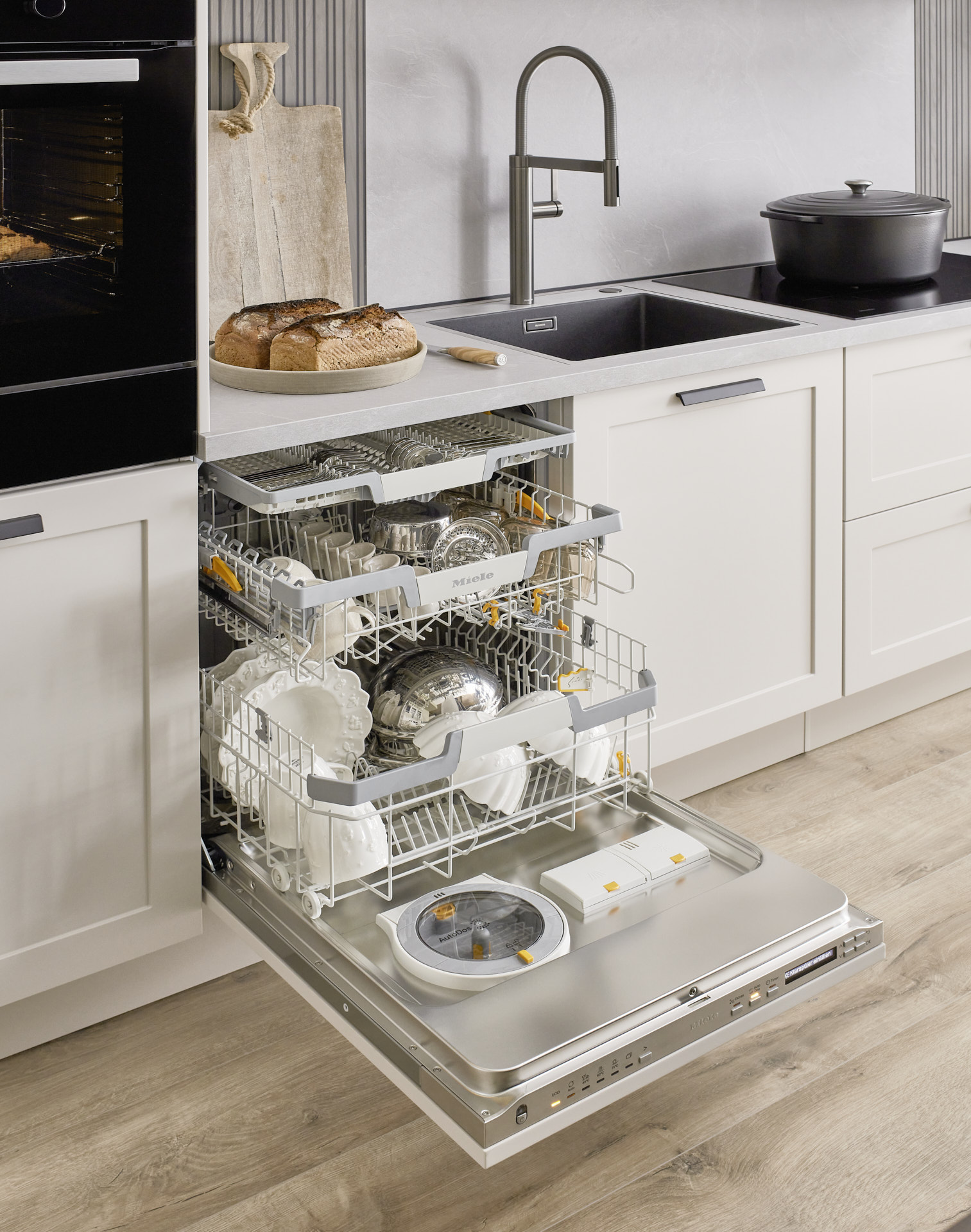 Miele Geschirrspüler, daneben noch Miele Induktionskochfeld und Messingspüle, Miele Einbaubackofen, Schubladen, Matt und Schiefernachbildung