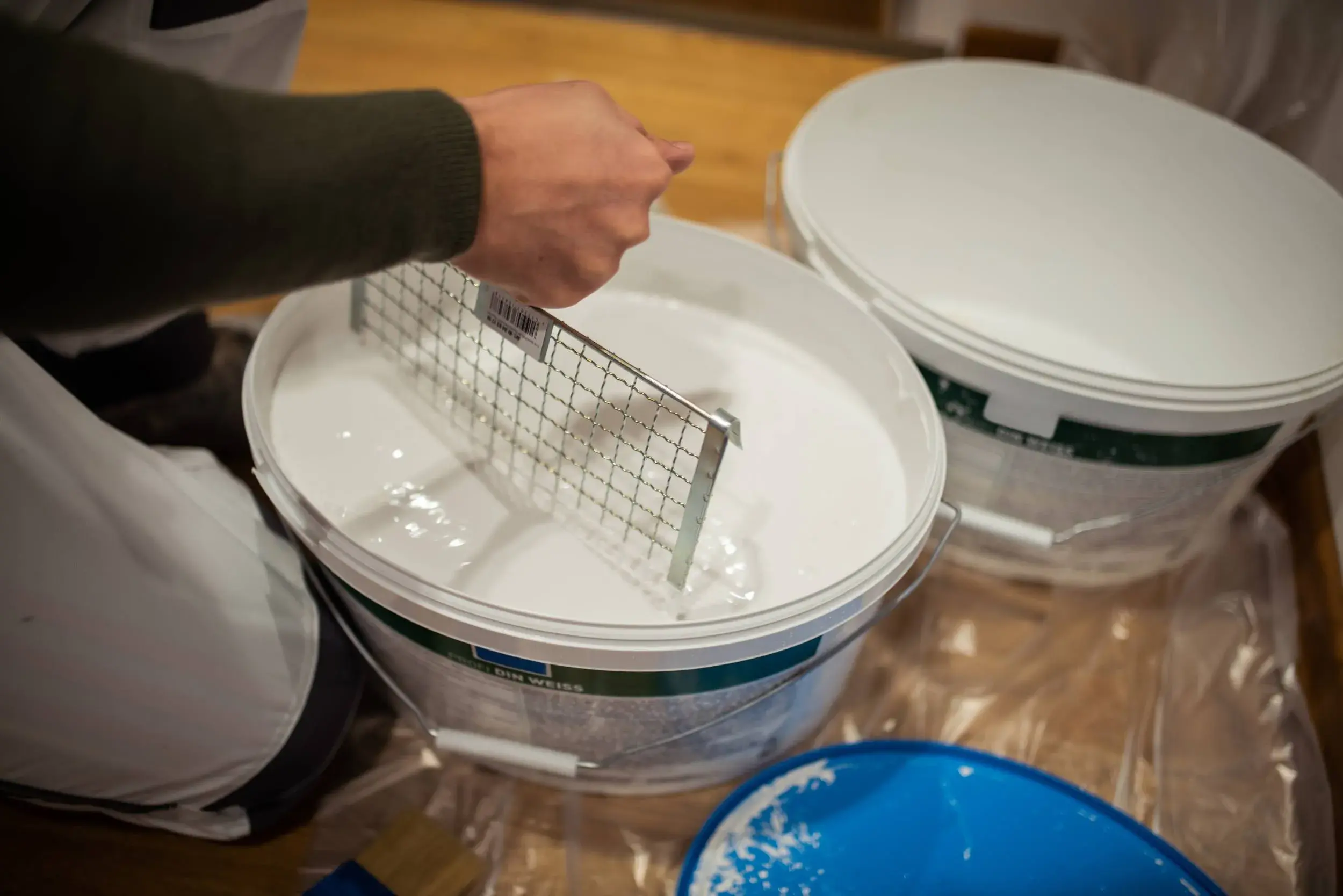 Zwei Eimer mit weißer Wandfarbe auf Folie, 2020